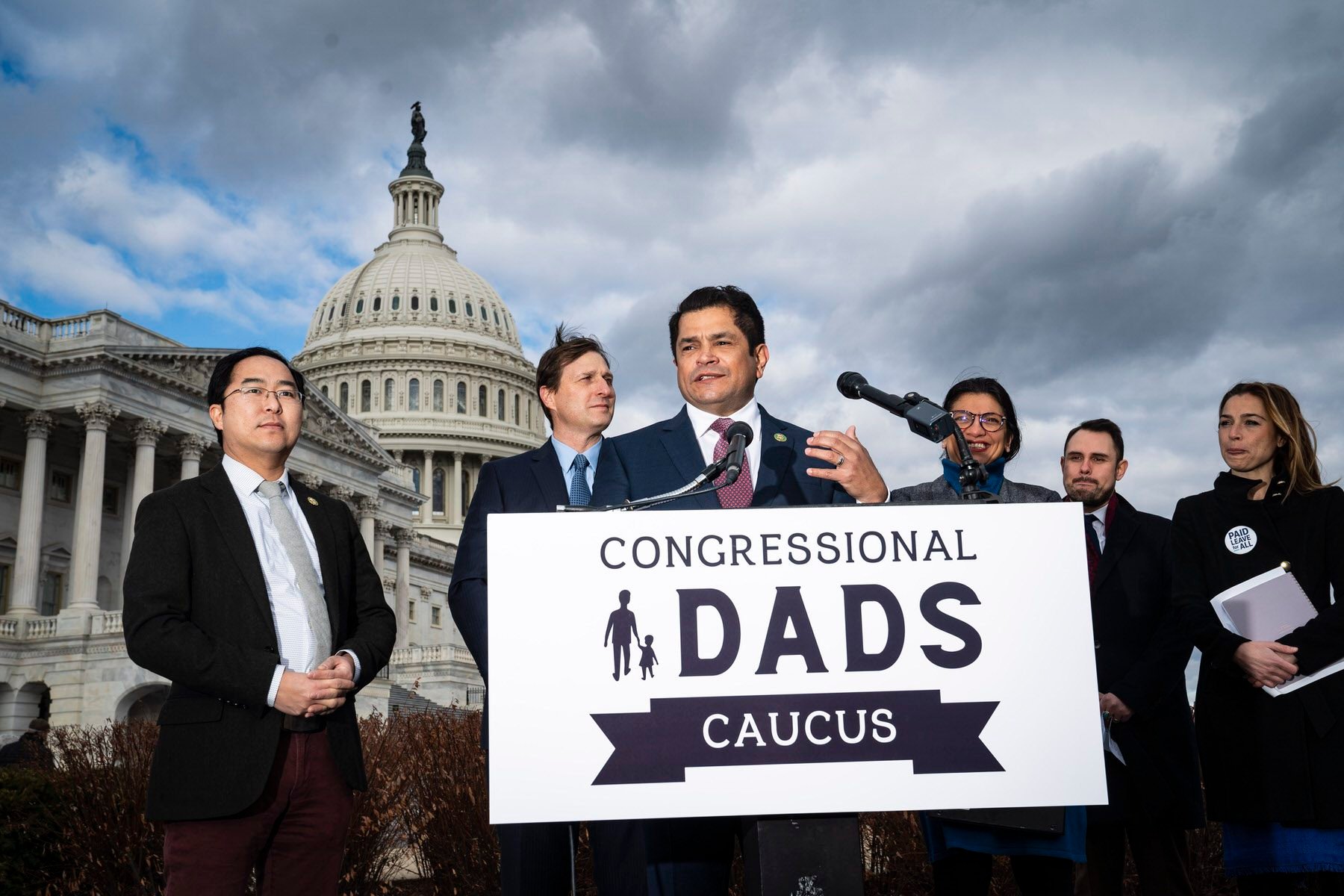 Rep. Jimmy Gomez and other members of Congress hold a news conference in front of the Capitol, with a sign that says "Congressional Dads Caucus"