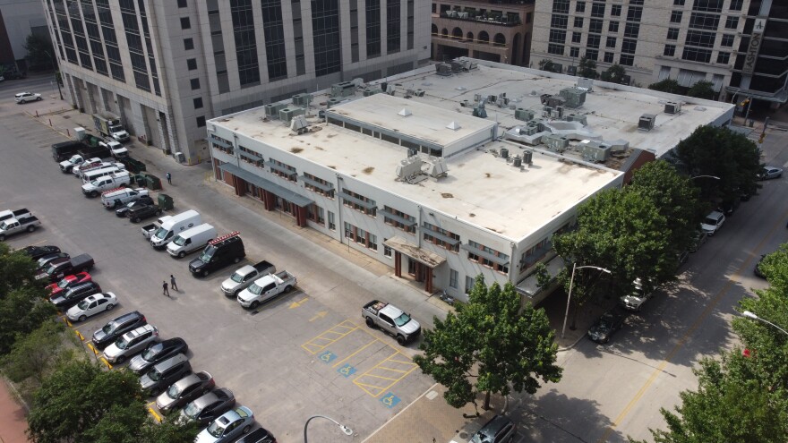  An aerial view of the Austin Transit Partnership headquarters at 203 Colorado Street. The two-story building is surrounded by tall office towers. 