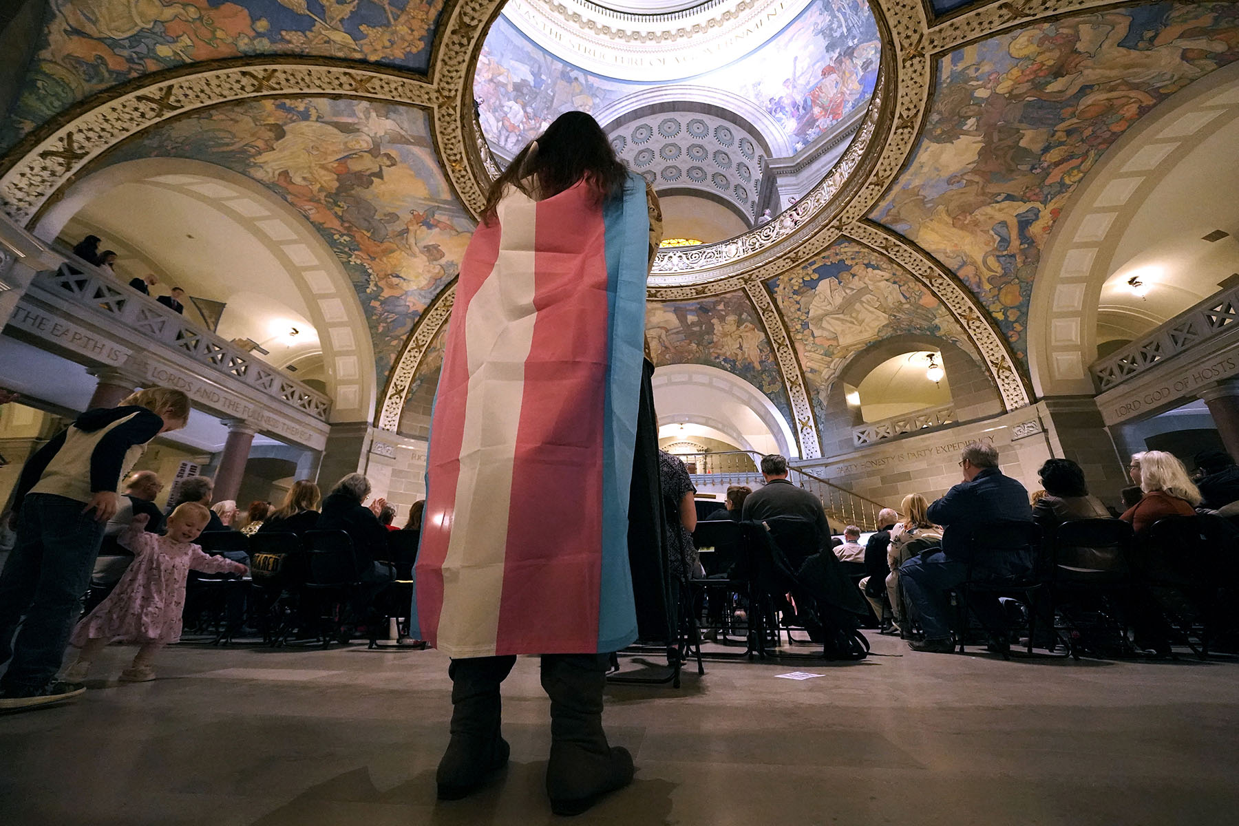 A counter-protester wears a transgender flag during a rally in favor of a ban on gender-affirming health care at the Missouri Statehouse.