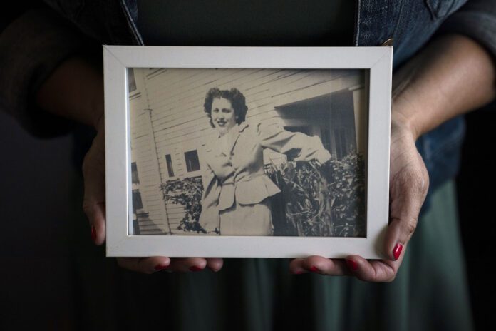 Hands hold a framed black and white photo of a woman smiling.