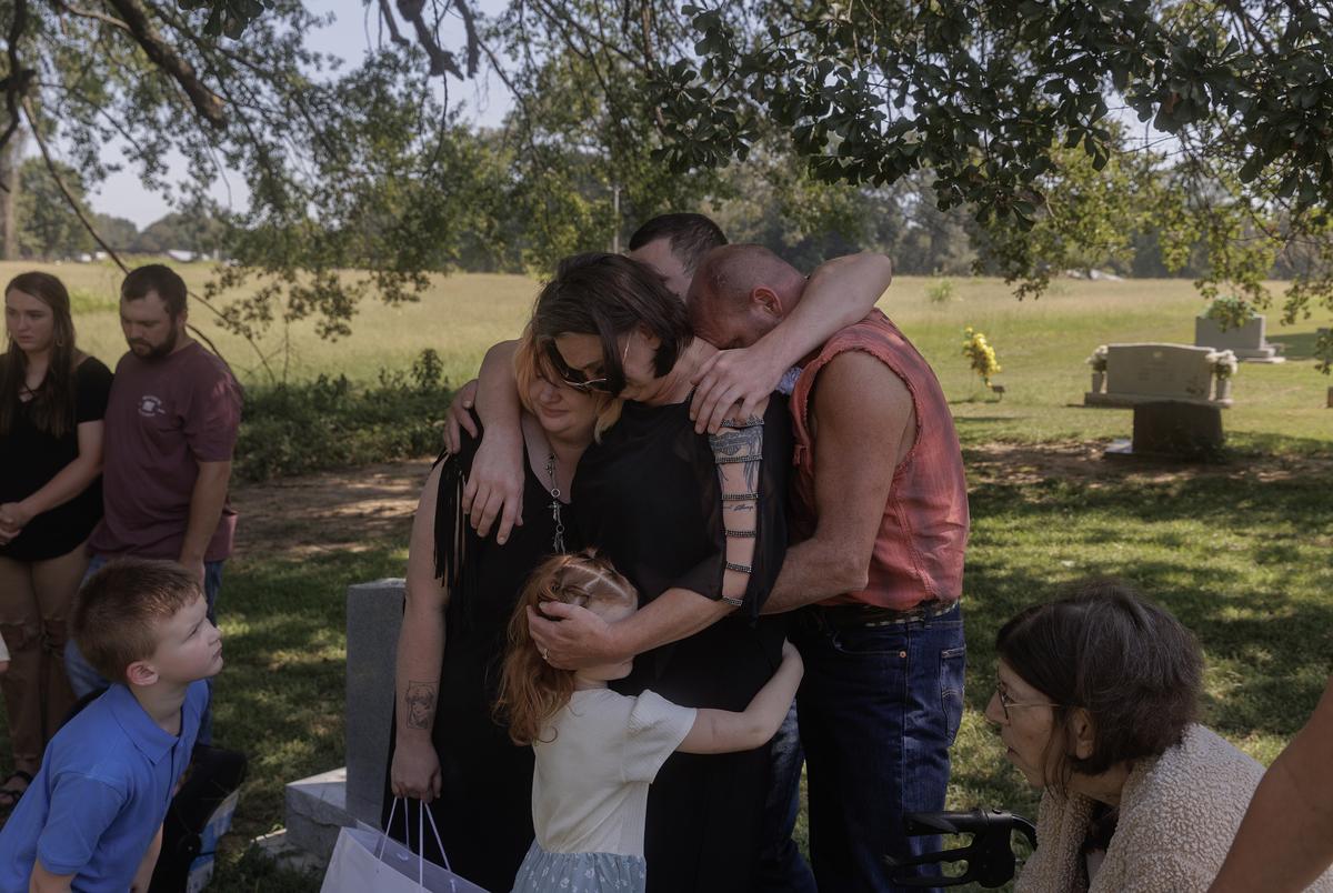The Langley family enwraps themselves around Miranda Michel as they grieve the loss of new born twins Perseus and Helios during a burial service in Broken Bow, Oklahoma on August 18, 2023.