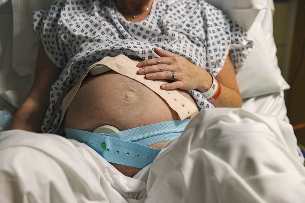 An unrecognisable mature pregnant woman lies on a hospital delivery bed as her baby