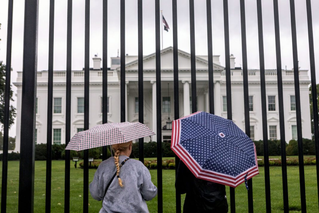 Tourists stand in front of the White House.